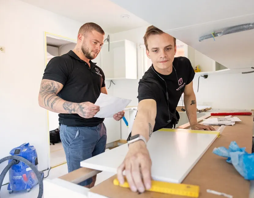 Timmie och en VVS-montör mäter upp inför monteringen av köket